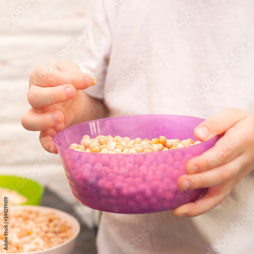 Hands of a small child playing with dry peas and semolina in multi-colored bowls
