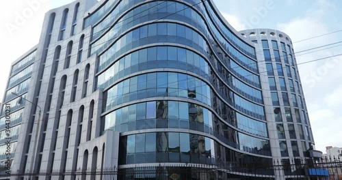 A courier in yellow clothes with a thermal backpack rides on a gyro scooter on the background of a business center with blue windows.