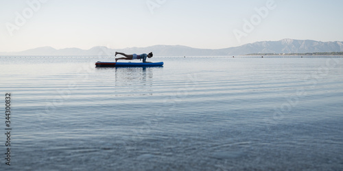 Young woman making plank position on sup board