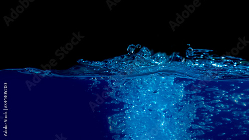 Beautiful blue water wave with splash and bubbles surface isolated on black.Abstract background.