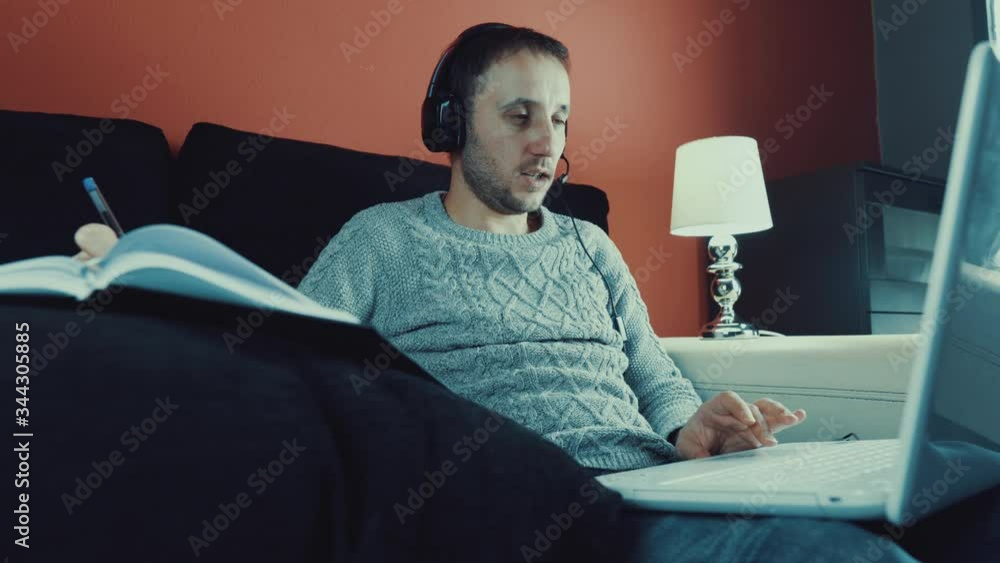 Hermoso joven trabajando con una computadora portátil mientras está sentado en la sala de estar tomando café durante la cuarentena debido al virus covid-19
