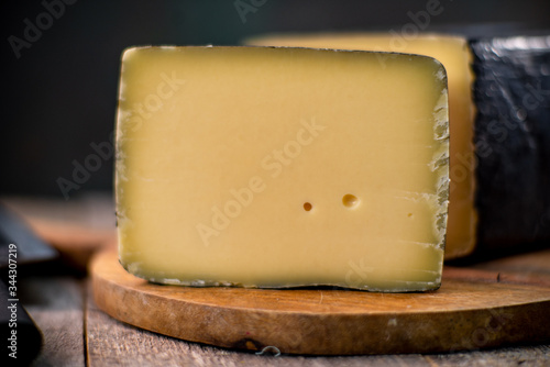 Medium hard cheese head gouda edam on wooden board with knife wooden texture daylight