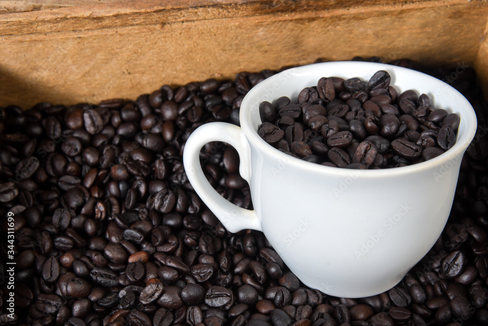 cup with roasted coffee beans inside, on the table with roasted beans cup with roasted coffee beans inside, on the table with roasted beans