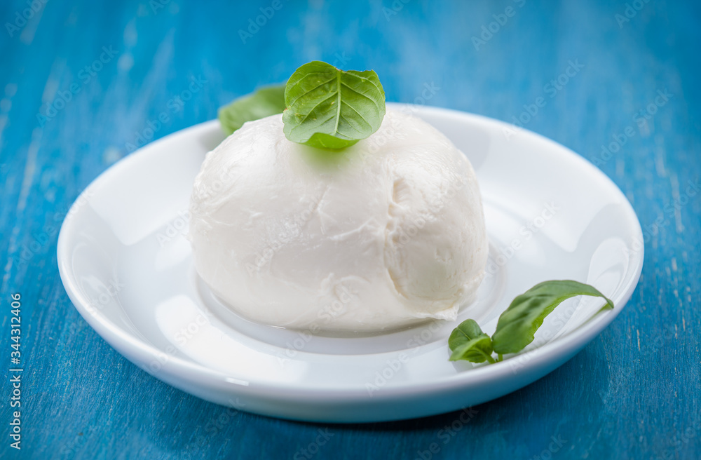 Portion of delicious buffalo mozzarella with basil leaves Portion of delicious buffalo mozzarella with basil leaves
