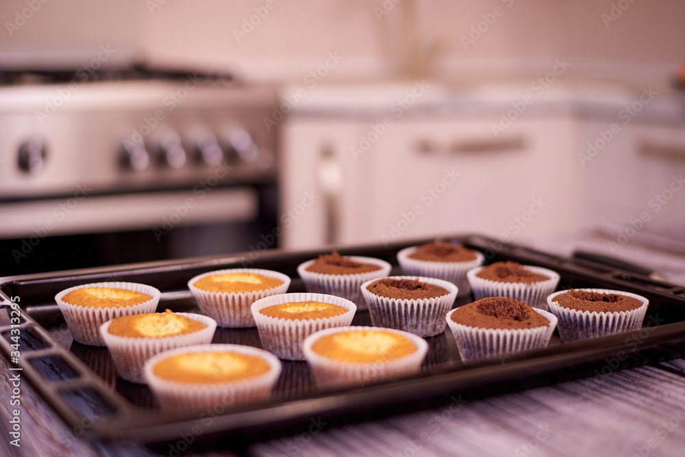 Cupcakes on a baking sheet on a table against the background of the kitchen. Cupcakes on a baking sheet on a table against the background of the kitchen.