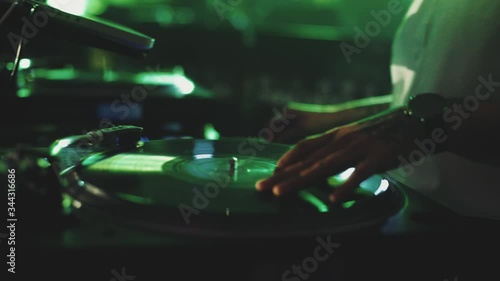 Modern style of music, front view of man with tattoo on the hand plays on the electronic musical device for djs with colorful illumination