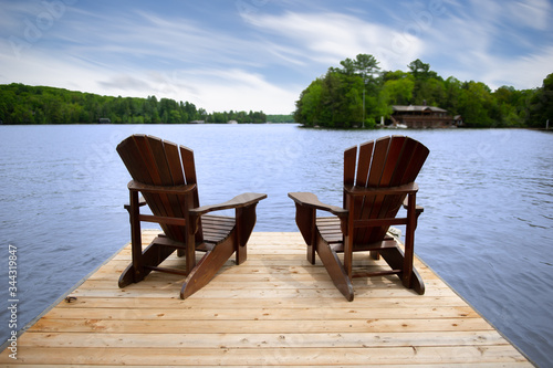 Fotótapéta Two Adirondack chairs on a wooden dock overlooking a calm lake