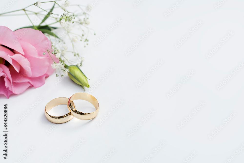 Pink flowers and two golden wedding rings on white background. Pink flowers and two golden wedding rings on white background.