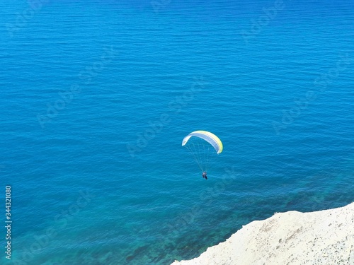The paraglider soars over the blue sea in a cloudless sky. Stunning view from the mountain to the Black sea.