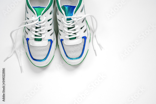 New stylish colorful sneakers with untied shoelaces on white background. Flat lay, top view, copy space minimal background. Concept love run.