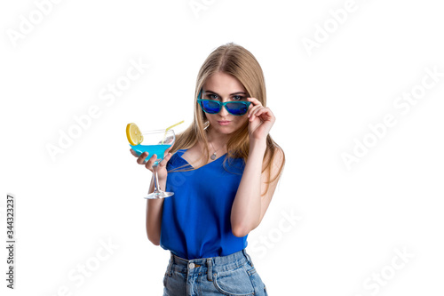 A girl in bright blue jeans and a blouse with a blue cocktail with lemon