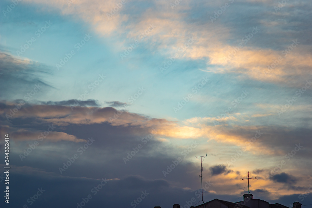 Clouds and roofs of houses in the evening sky
