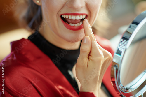 trendy woman looking in mirror and checking teeth photo