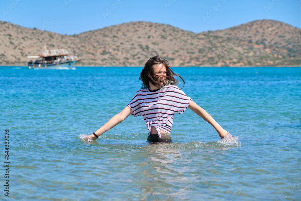 Teenager girl is touching, enjoying sea water in the bay Teenager girl is touching, enjoying sea water in the bay