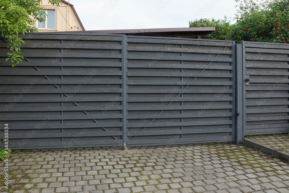 architecture of closed gray wooden gate on the sidewalk on a rural street architecture of closed gray wooden gate on the sidewalk on a rural street