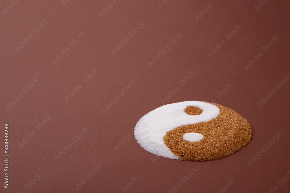 Yin yang symbol made with refined white sugar and cane sugar. Visual metaphor comparing both sugars. Cane sugar versus refined sugar.