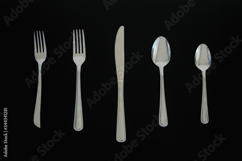 Top view of a silverware placed on a dark table