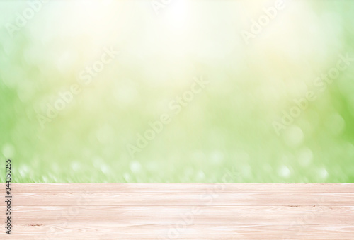 Abstract green defocused background with wooden base and sun light effect. Empty mockup, blurred backdrop with bokeh