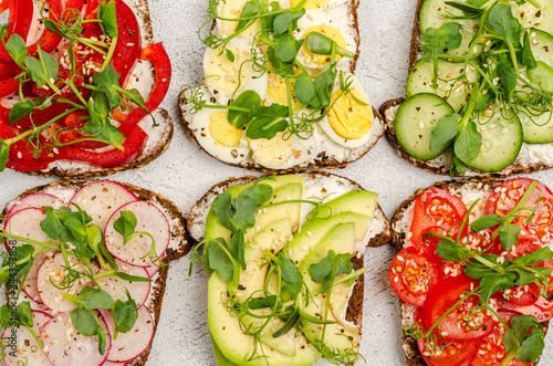 ariety of mini sandwiches with cream cheese and vegetables on a light background. photo