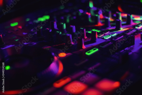 Colorful lights on DJ Mixer with many knobs in night club party