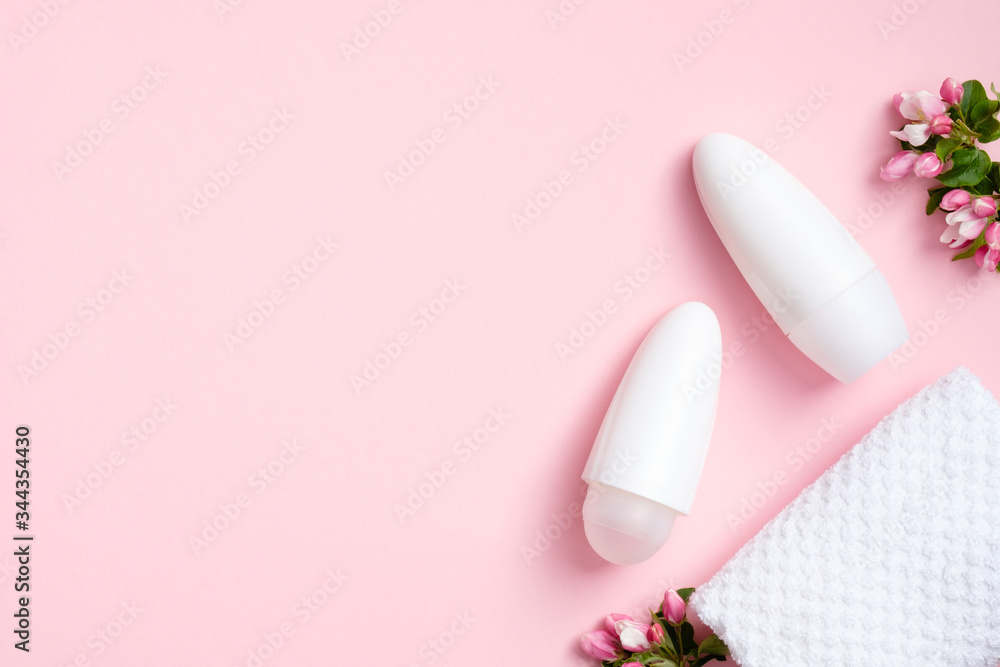Roll-on deodorant bottles with blossom flowers and towel on pink background. Flat lay, top view. Natural organic cosmetic packaging for underarm skin care, sweat protection Roll-on deodorant bottles with blossom flowers and towel on pink background. Flat lay, top view. Natural organic cosmetic packaging for underarm skin care, sweat protection