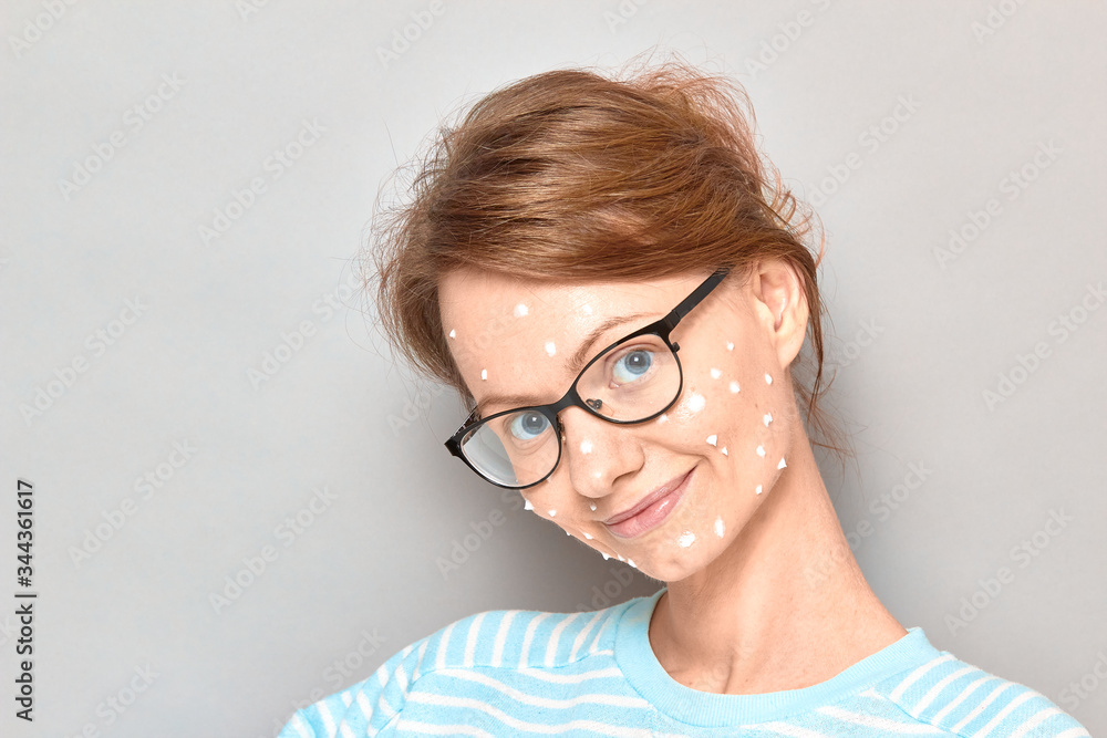 Portrait of happy girl with white drops of face cream on skin