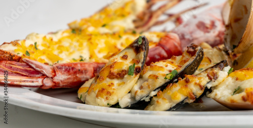 Assortment of baked seafood with cream and cheese on a white plate