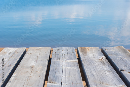 Close-up of picnic table with blue lake water in background on sunny day
