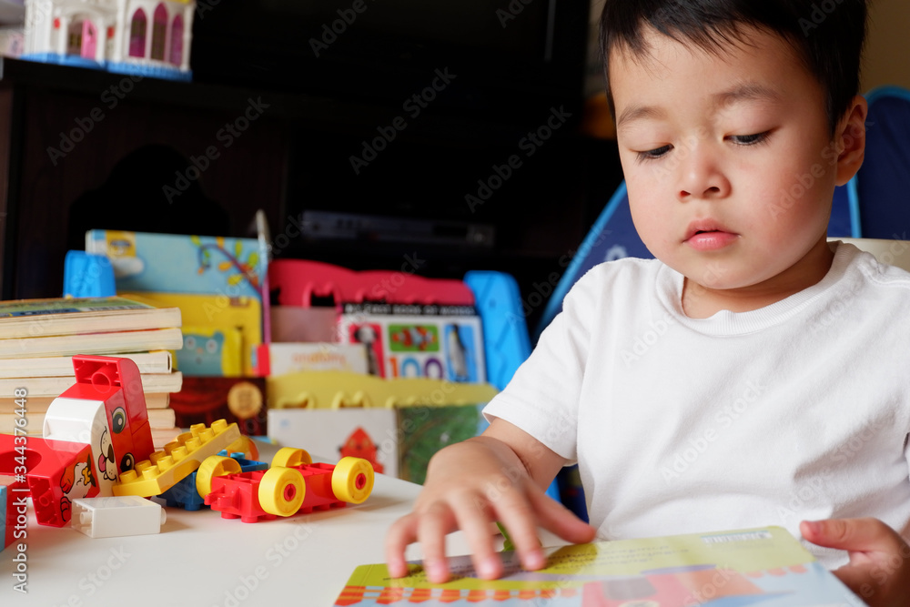 Fototapeta premium An Asian boy is playing a toy on a white table.