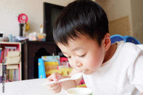 An Asian boy is eating snack and drinking water.