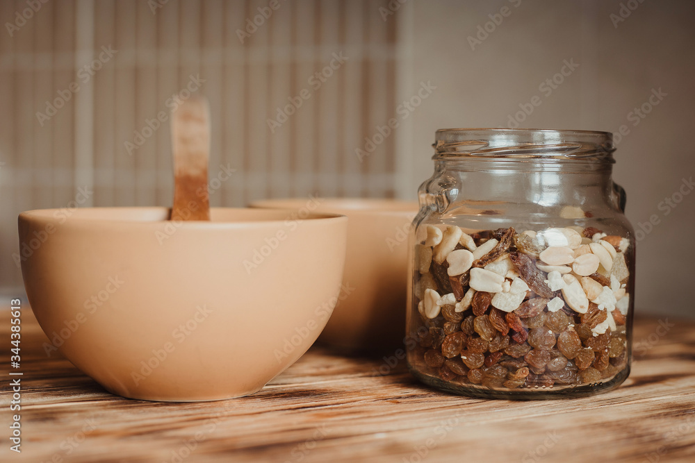 Oatmeal in a wooden spoon on a wooden background and dried fruit in a glass jar. The concept of a healthy diet and healthy lifestyle. Oatmeal in a wooden spoon on a wooden background and dried fruit in a glass jar. The concept of a healthy diet and healthy lifestyle.