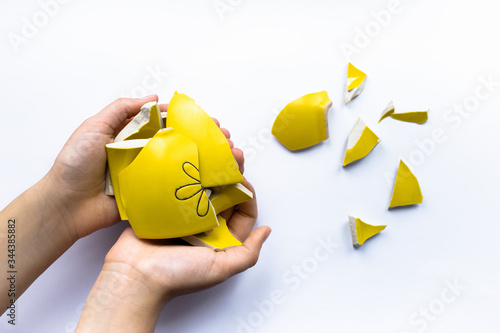 Photography Yellow broken cup in the hand isolated on white background