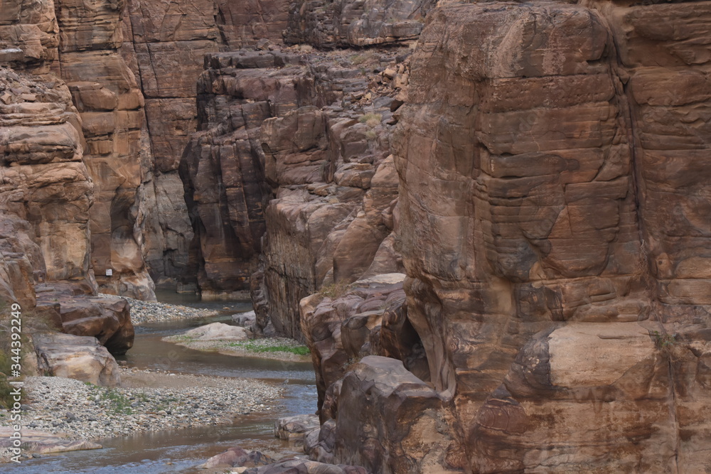 Entrance to the Wadi Mujib canyon in Jordan. Steep rocks and a rapid flowing river carved. Difficult crossing and attraction for tourists on the water route. Entrance to the Wadi Mujib canyon in Jordan. Steep rocks and a rapid flowing river carved. Difficult crossing and attraction for tourists on the water route.