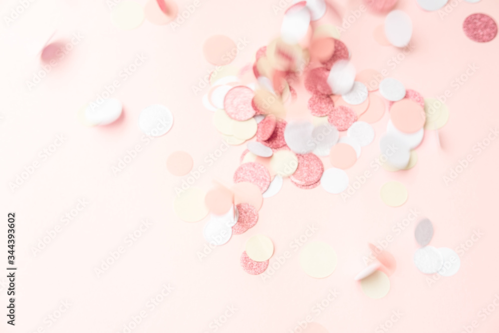 Multicolor pink, gold and white confetti falling on the pastel light pink background, holiday celebration backdrop with place for text