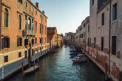 A scenic view of a beautiful Venetian canal on a warm sunny day with colourful houses and architecture running along the water in the town of Venice, Italy © Matthew