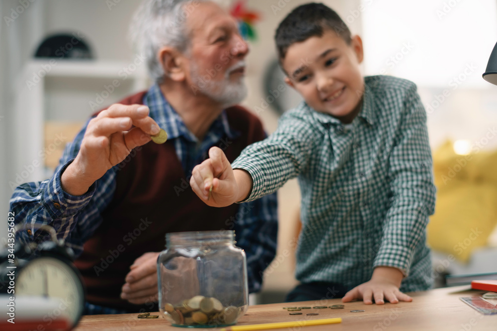 Grandpa and grandson saving money. Grandfather teaching grandchild how to save money. Grandpa and grandson saving money. Grandfather teaching grandchild how to save money.