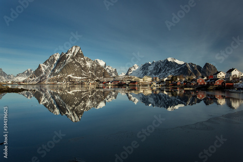 View of beautiful Sacrisoya village in winter time with montains in background with light of sunrise. Lofoten, Norway. © danmir12
