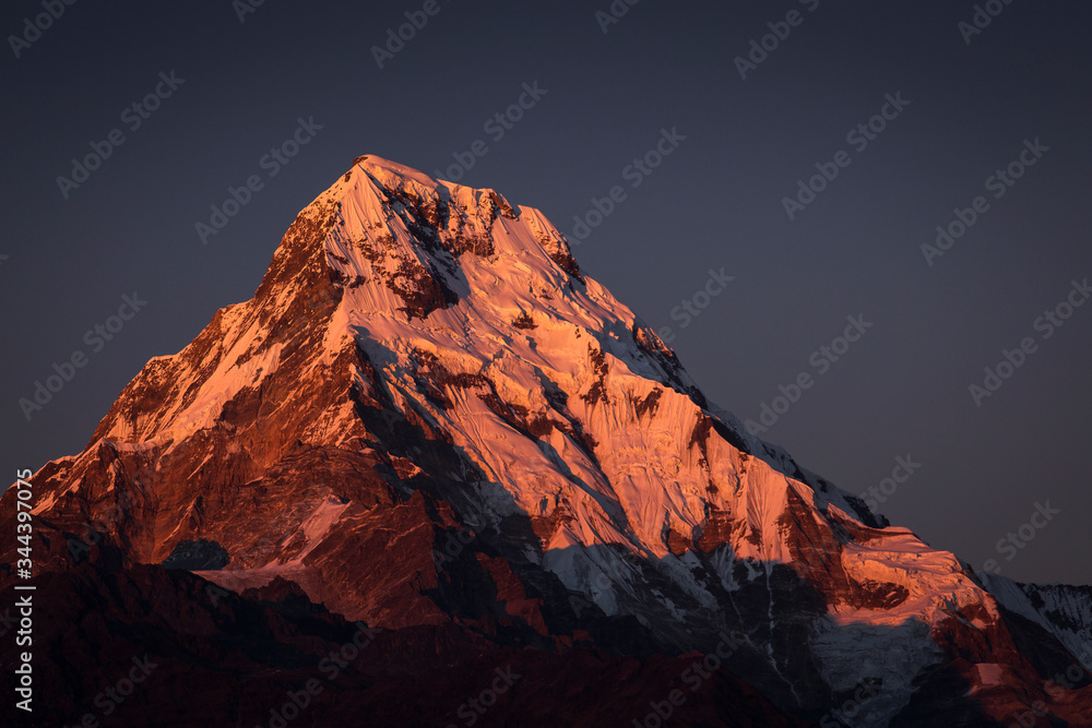 View of Annapurna South at sunset from Poon Hill with buddhist flags. Himalaya Mountains, Nepal