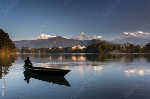 Beautiful landscape with Phewa Lake and boat on lake, mountains in background also as reflectaion on lake.  Machapuchare-FIshtail, Annapurna and many others. Pokhara, Nepal © danmir12