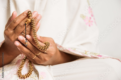 Muslim woman praying close up image of hands as she holds prayer beads,tasbih.