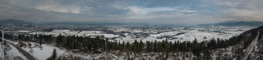 Winter panorama over white plains and fields of southern ljubljana marshes and with clouds, with mountains and dense clouds in the background. Picture taken close to Verd and Borovnica village.