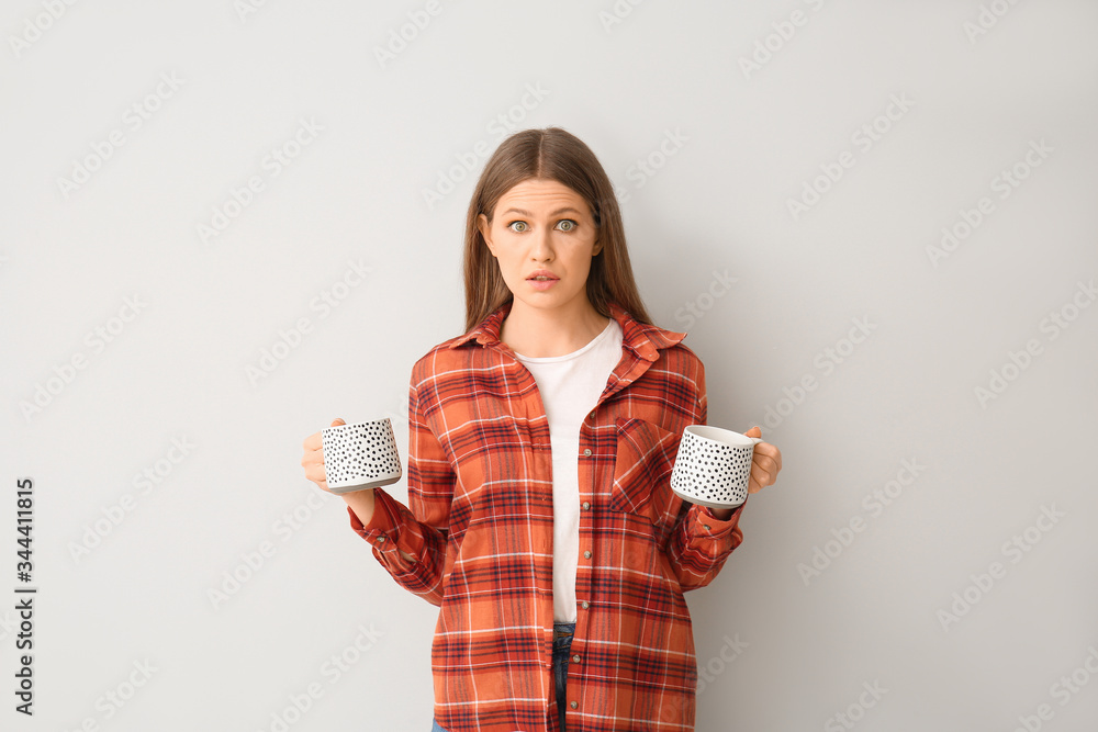 Surprised young woman with coffee on light background Surprised young woman with coffee on light background