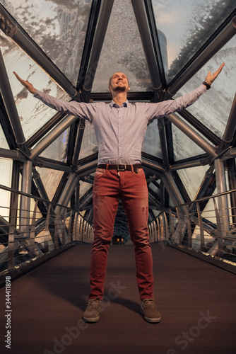 a young businessman is happy to have defended his project and made an important deal, he makes a wide gesture with his hands, spreading them out to the sides and raising them above him