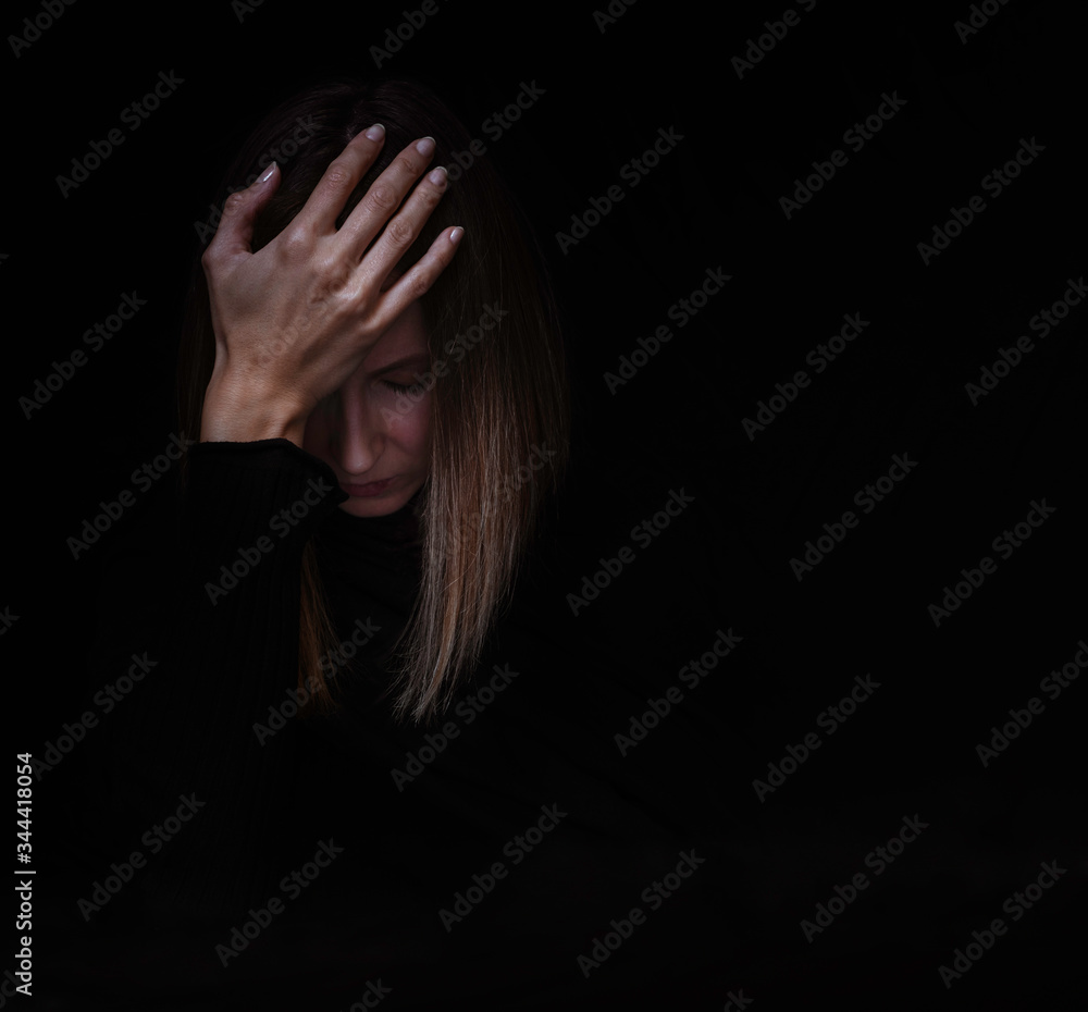 Young caucasian woman feeling sad and depressed in self-isolation, suffering in mental health, isolated on the black background, dark mood. Young caucasian woman feeling sad and depressed in self-isolation, suffering in mental health, isolated on the black background, dark mood.