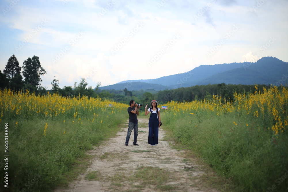 Women and men take pictures in the crotalaria juncea field in Rayong, Thailand.