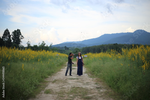 Women and men take pictures in the crotalaria juncea field in Rayong, Thailand. © pantkmutt