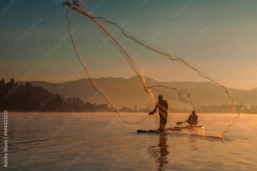 fisherman who is throwing nets with his friend in the morning