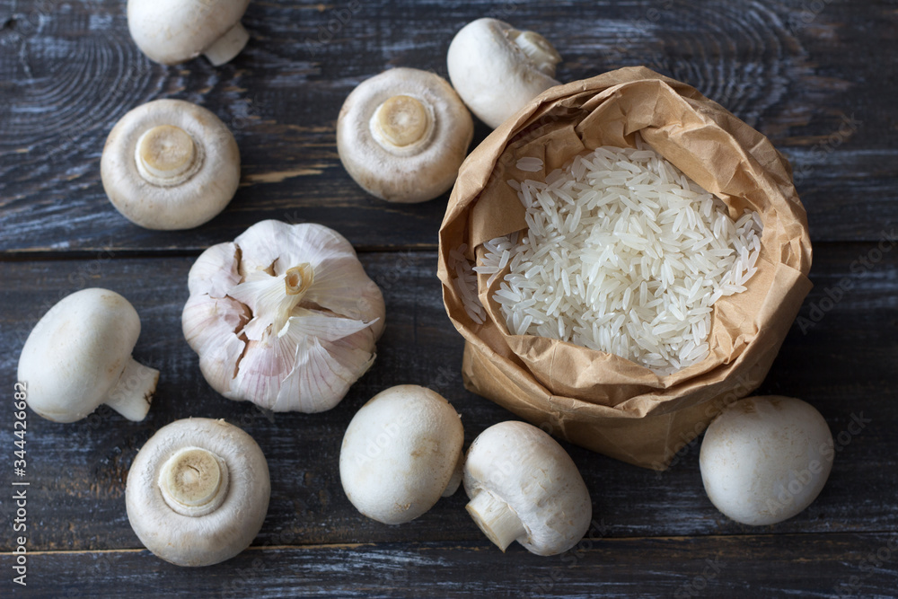 Ingredients for a delicious vegan dish. White basmati rice, garlic and champignons on a wooden table, top view, horizontal