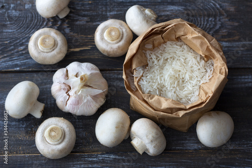 Ingredients for a delicious vegan dish. White basmati rice, garlic and champignons on a wooden table, top view, horizontal