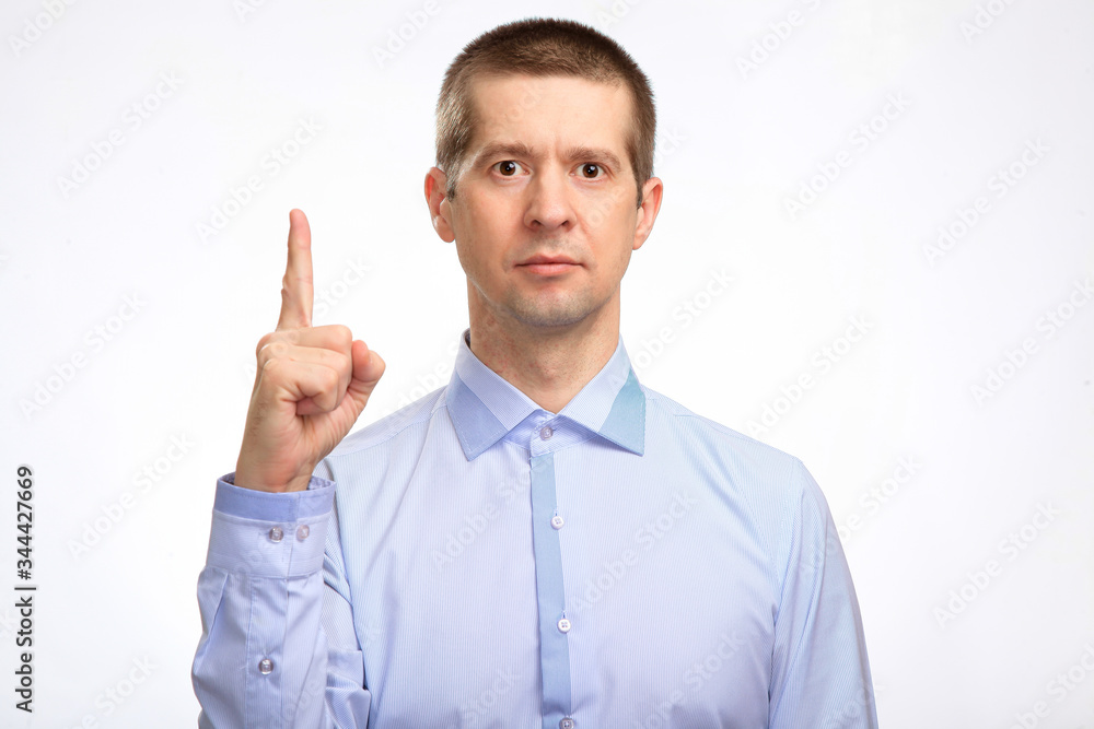 successful business man points his index finger in up, in a blue light casual shirt, looking into the camera. Isolated successful business man points his index finger in up, in a blue light casual shirt, looking into the camera. Isolated